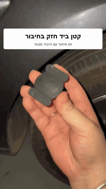 תג האיתור הקטן בתוך נרתיק מגנטי מוצג ביד לצד הרכב